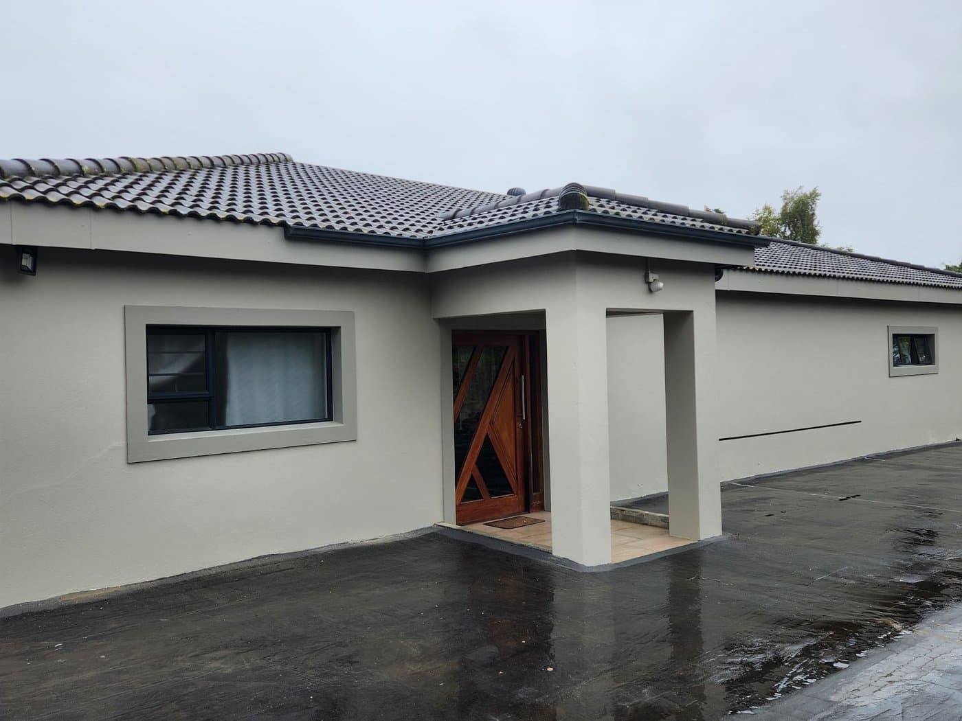 A finished single storey home in grey render with a tiled roof