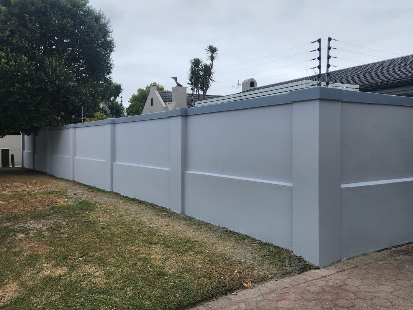 A plastered and painted boundary wall running the length of a garden