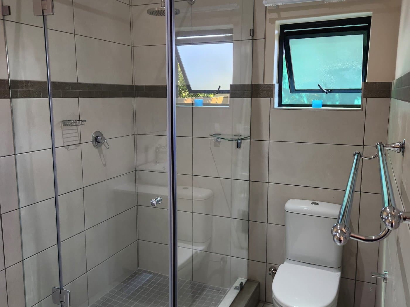 A finished bathroom with a frameless glass shower and tiled walls