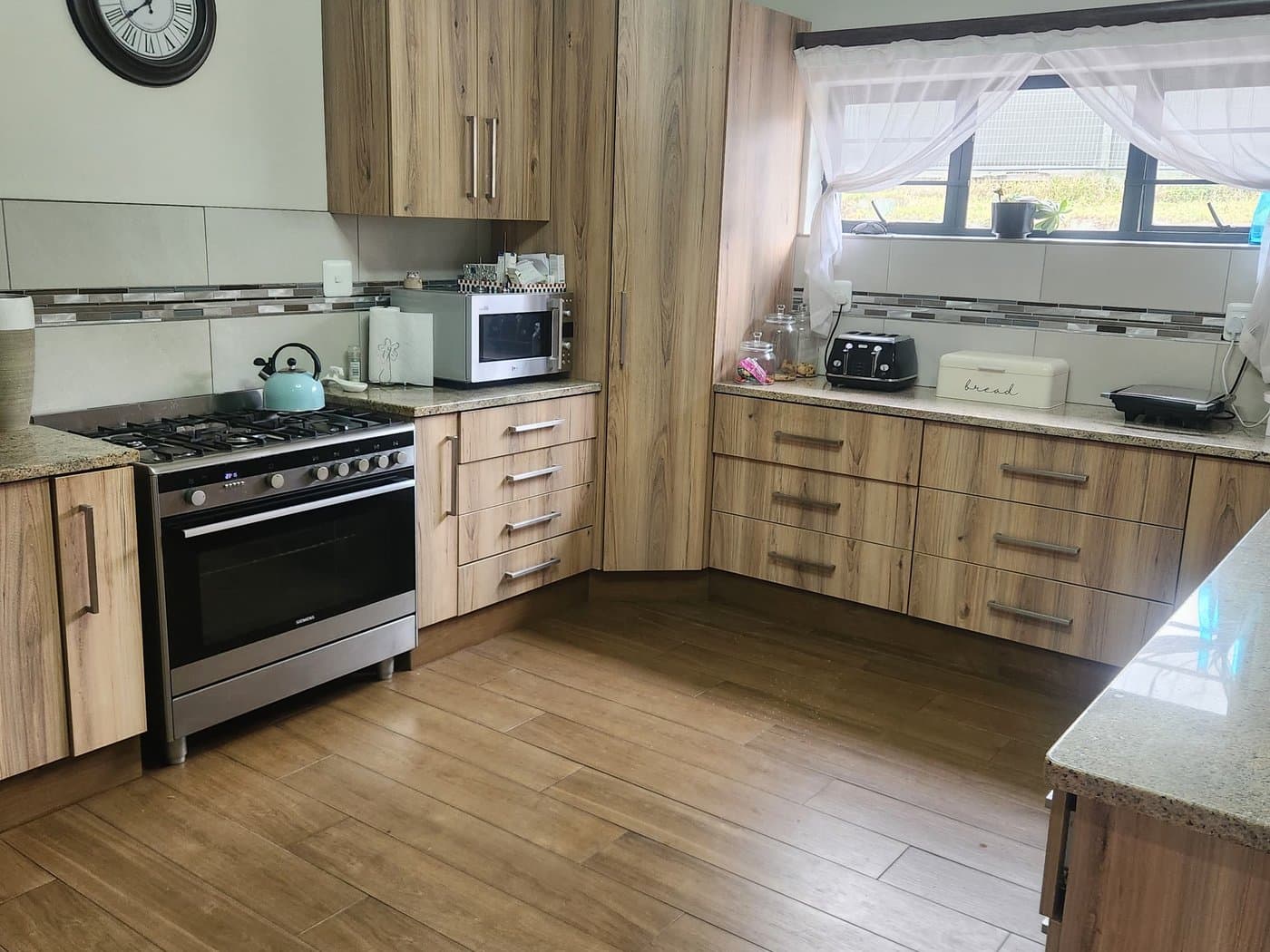 A fitted kitchen with timber cabinetry, gas hob and stone tops