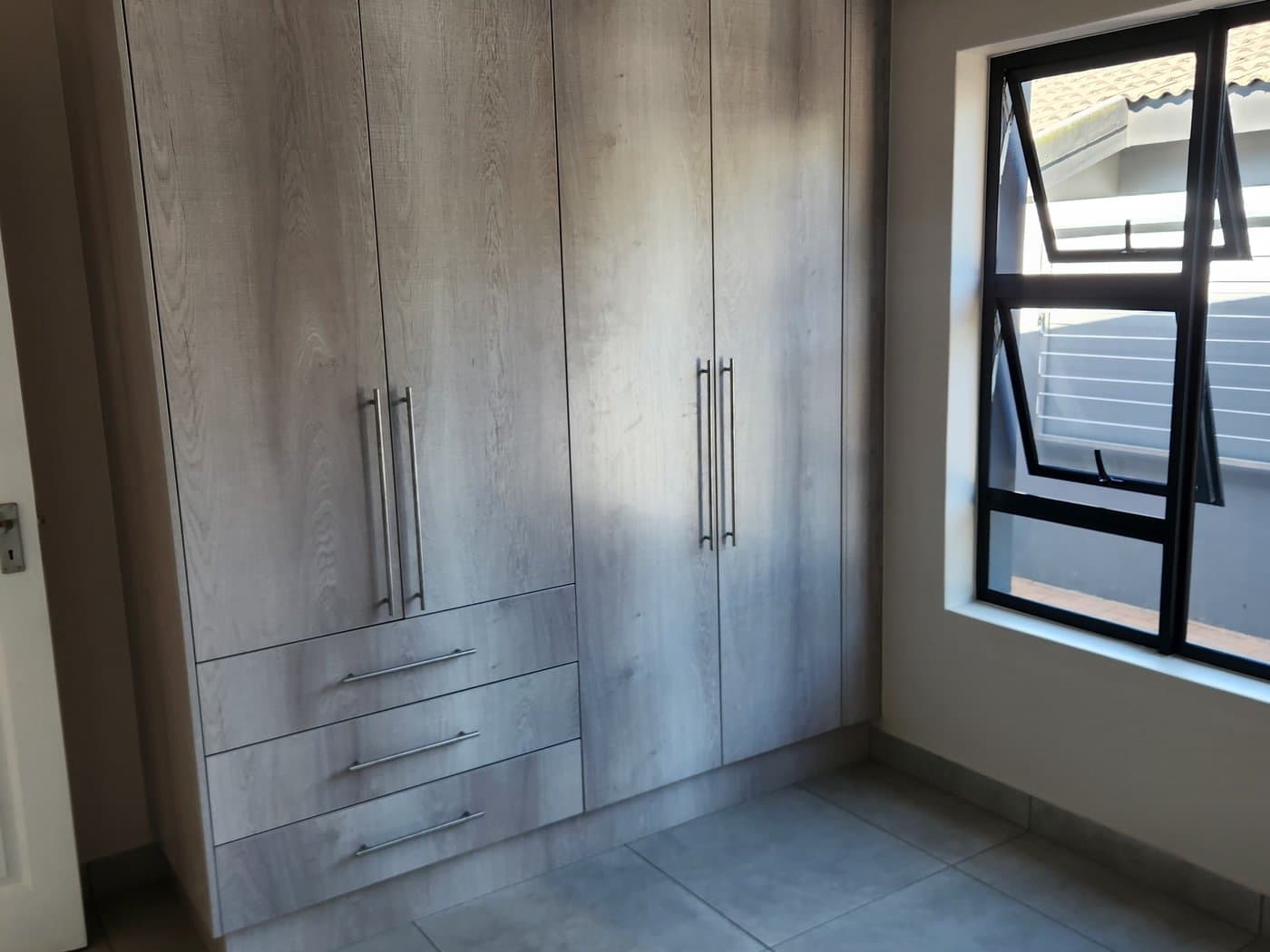 A built-in bedroom wardrobe with fitted doors and long handles