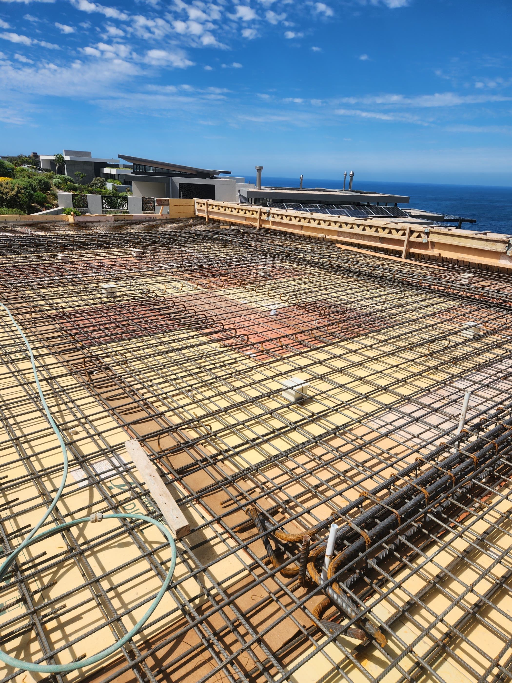 A large reinforced slab tied and ready to pour, the sea beyond the site