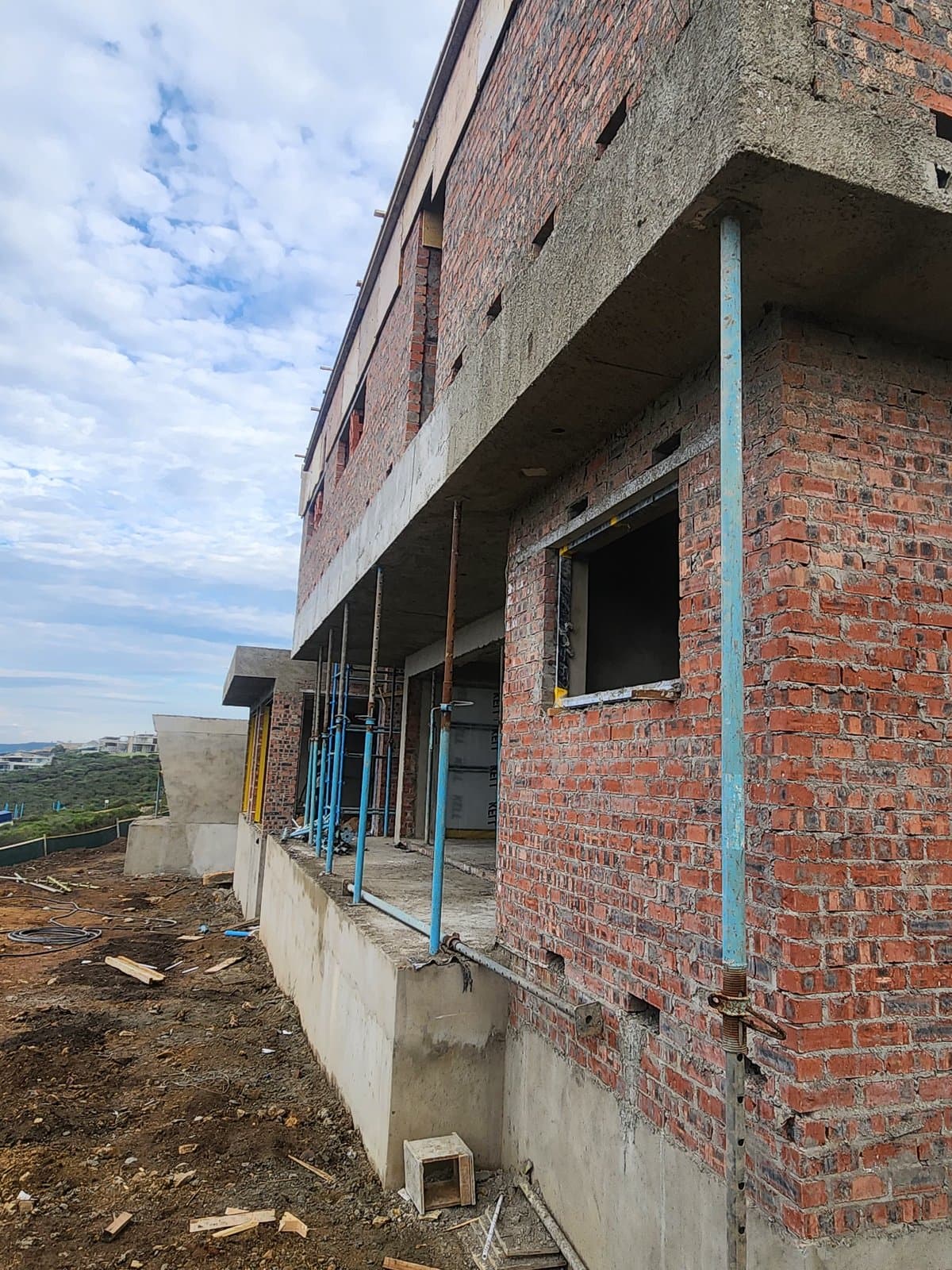 A two storey brick shell standing before plaster, above a valley