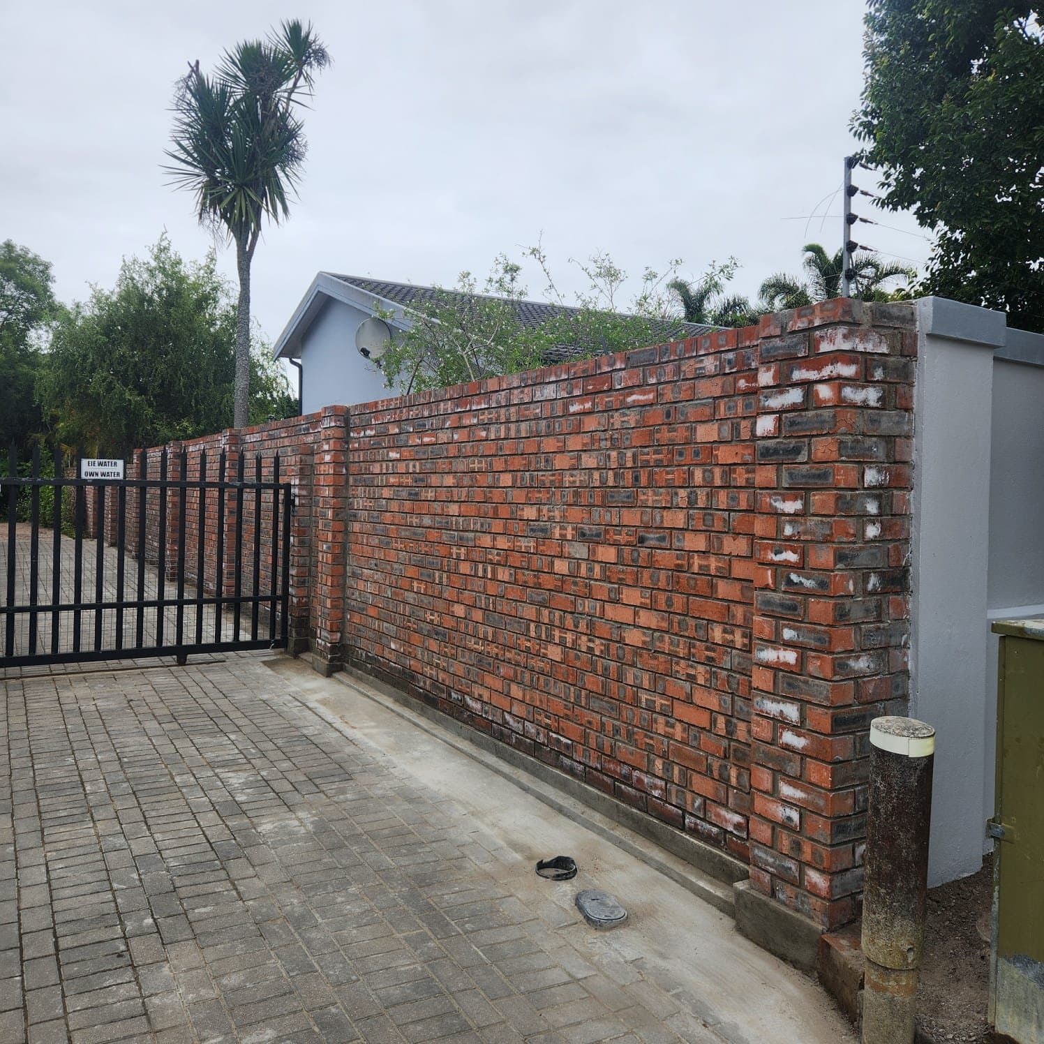 A face brick boundary wall with a steel driveway gate