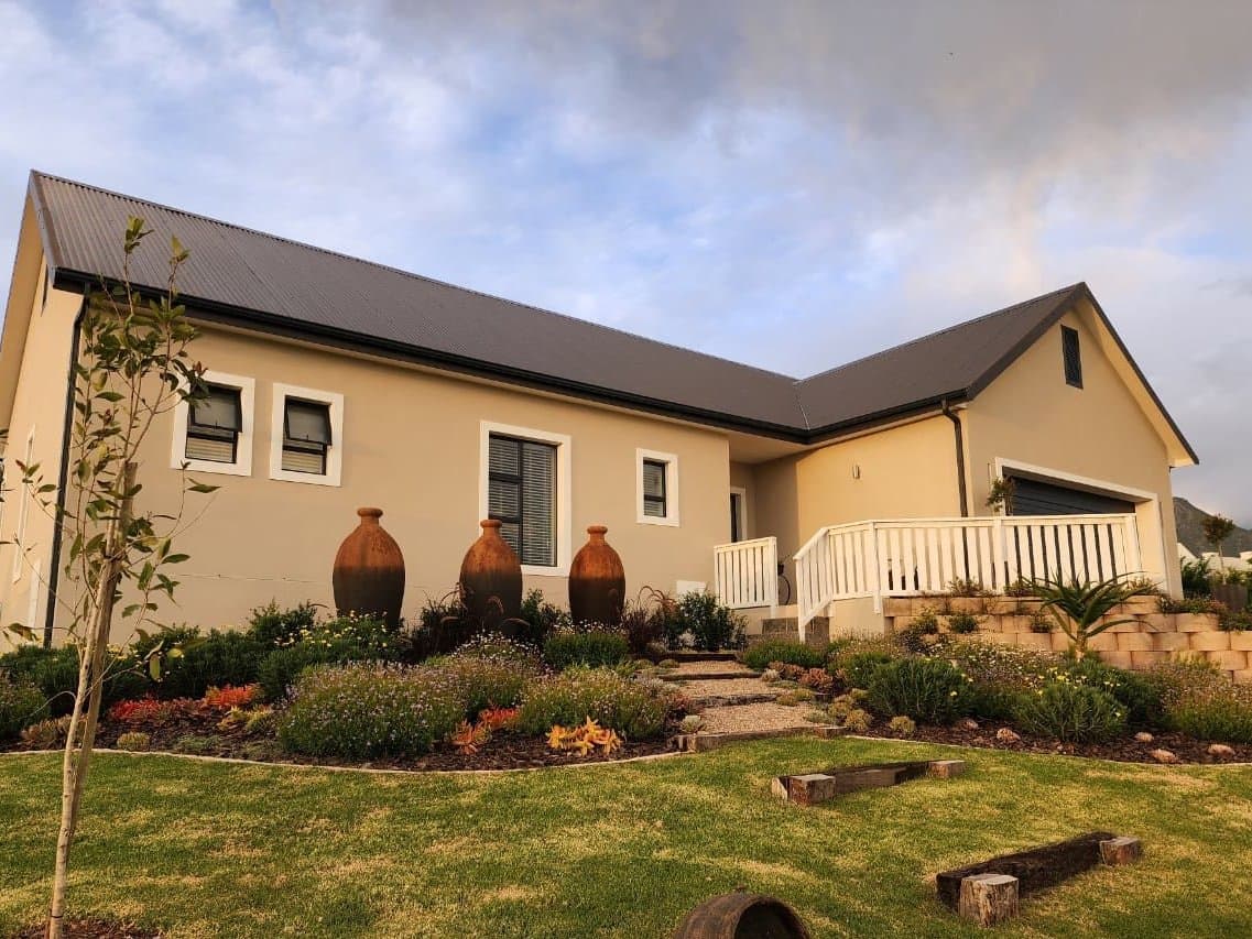A finished home with a pitched roof, planted beds and clay pots along the front