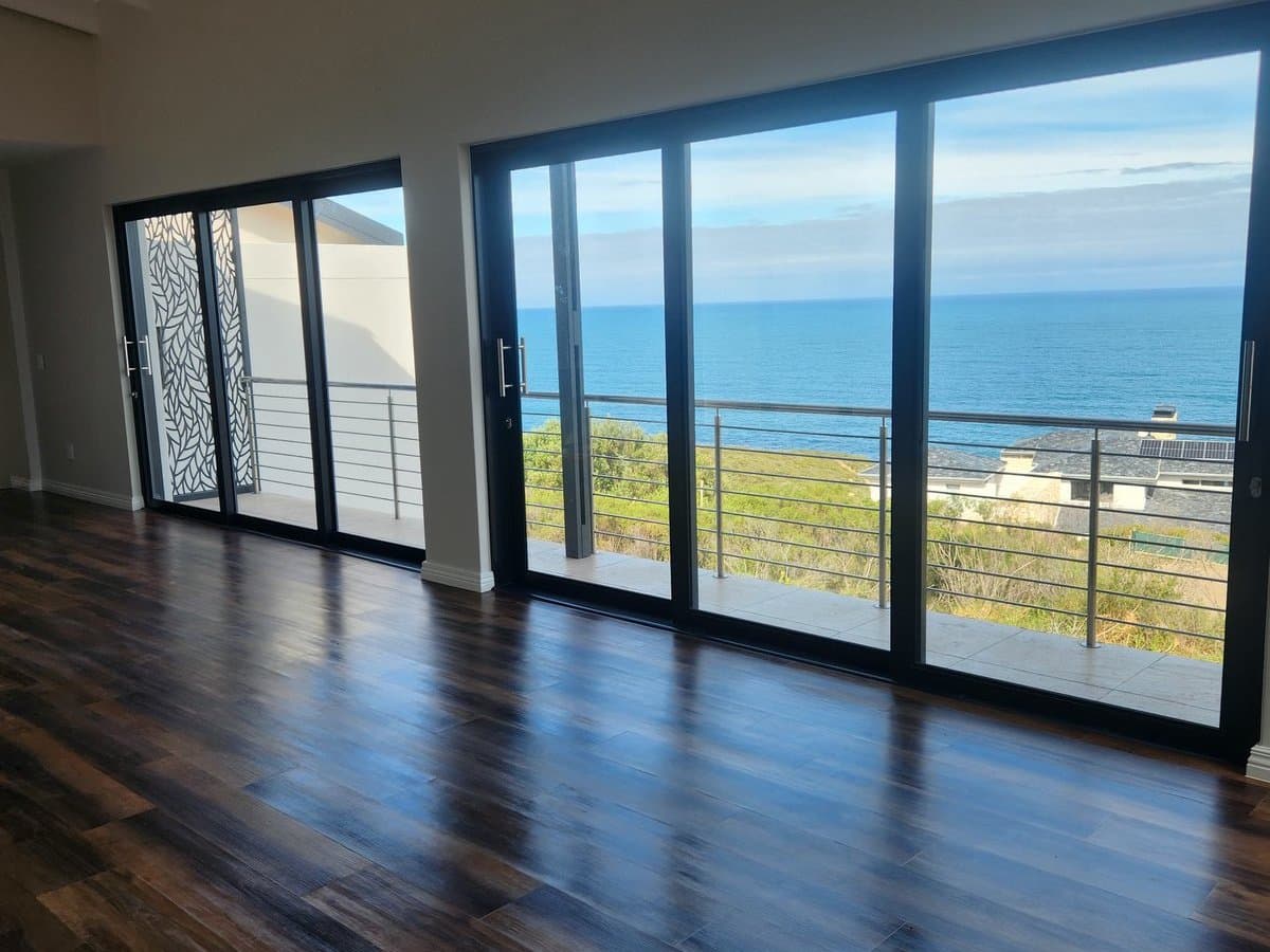 A finished living room with timber floors and full height sliding doors onto the sea