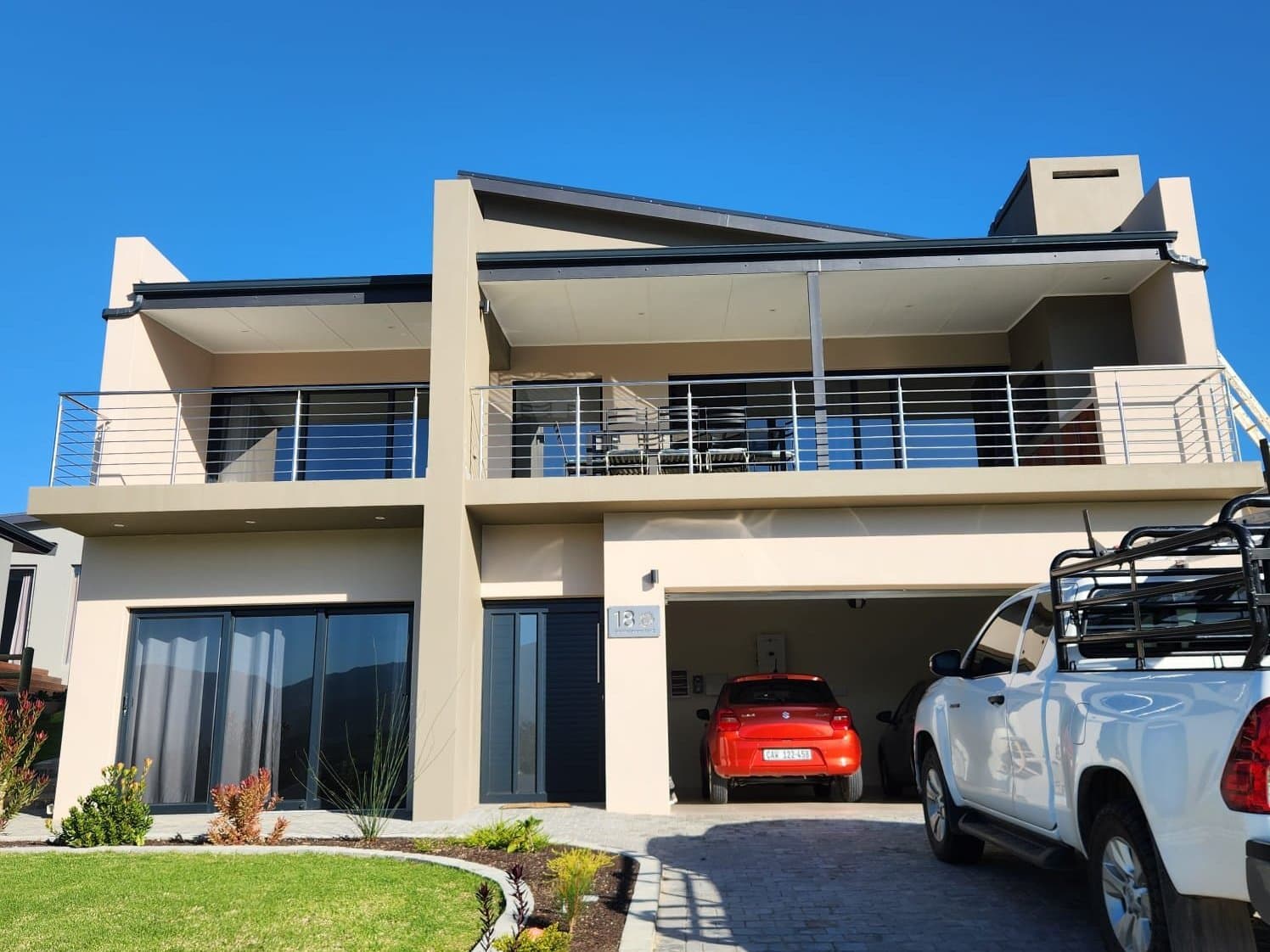 A completed two storey home with a covered balcony and double garage, seen from the driveway