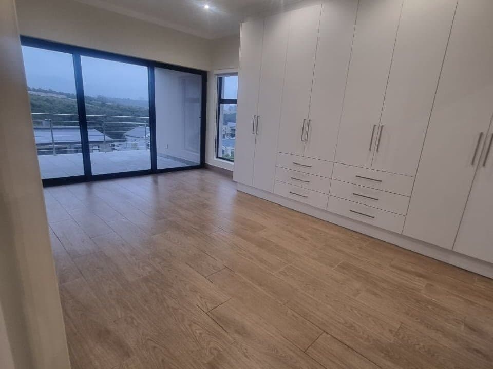 A finished bedroom with fitted white wardrobes, timber floors and sliding doors